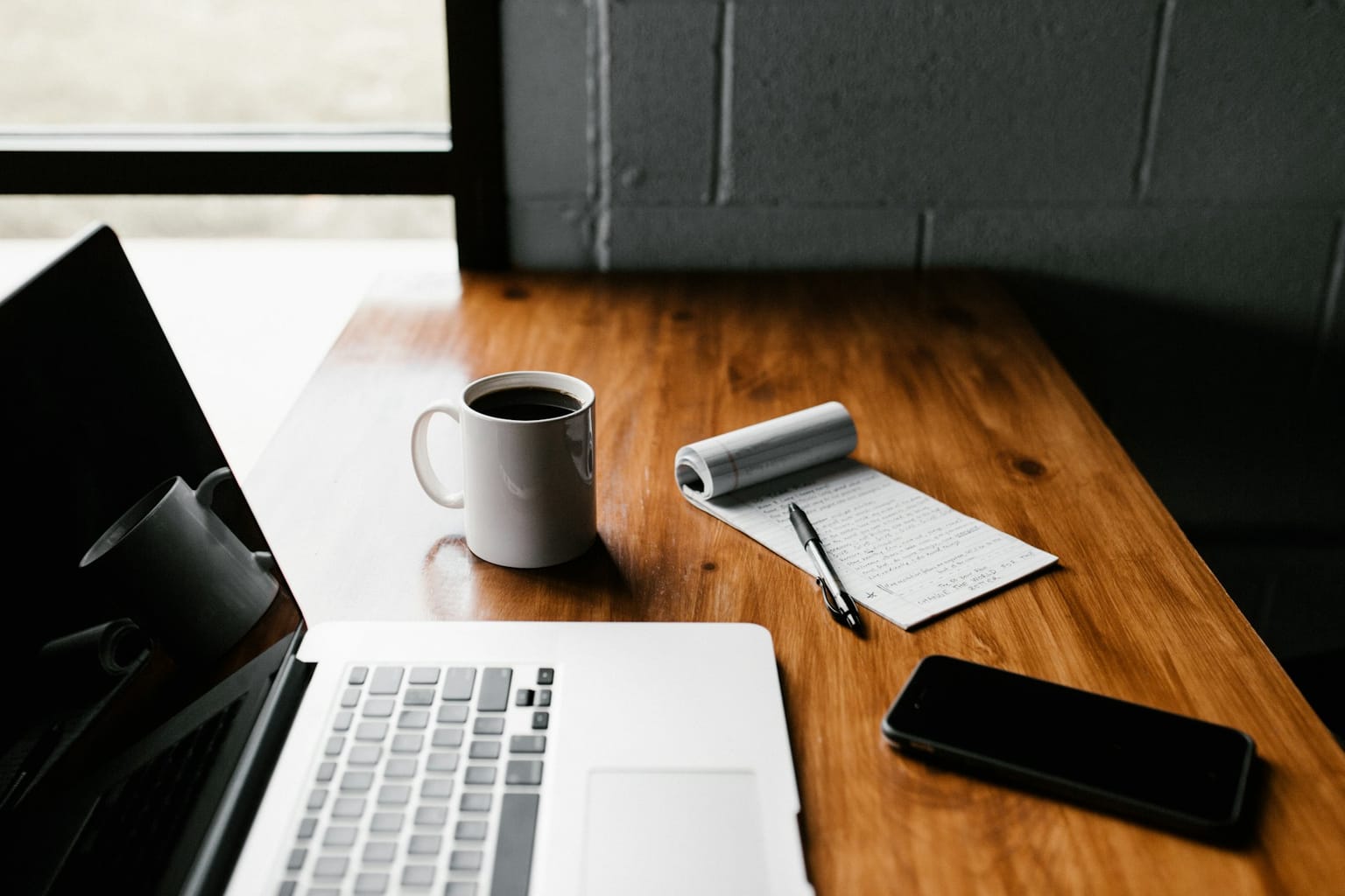 A planner, laptop and coffee on a desk